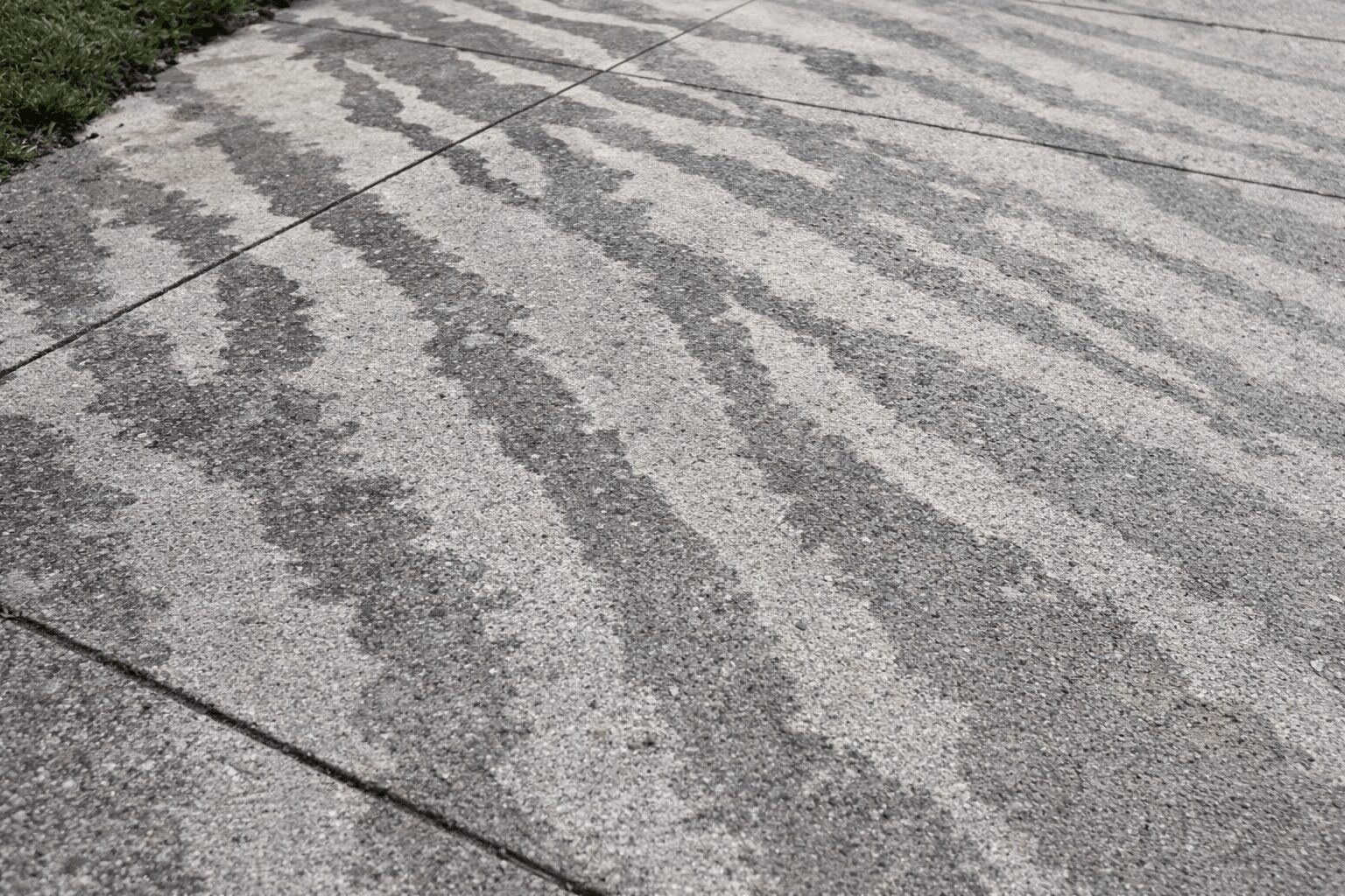Close up of etching and tiger stripes on a concrete driveway caused by an amateur DIY pressure wash.